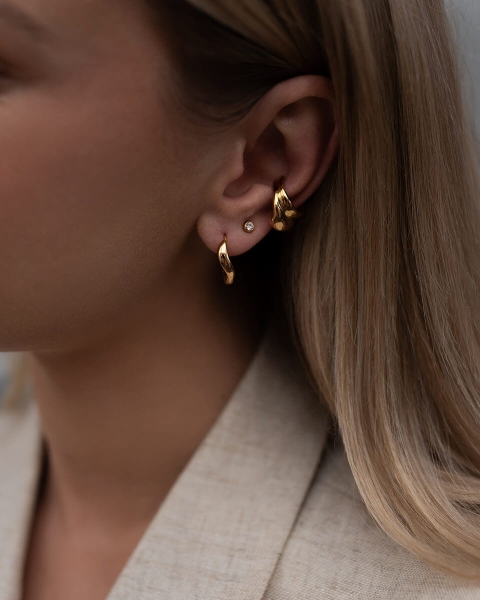 Złote kolczyki o rzeźbionej strukturze, tworzące efekt biżuterii artystycznej